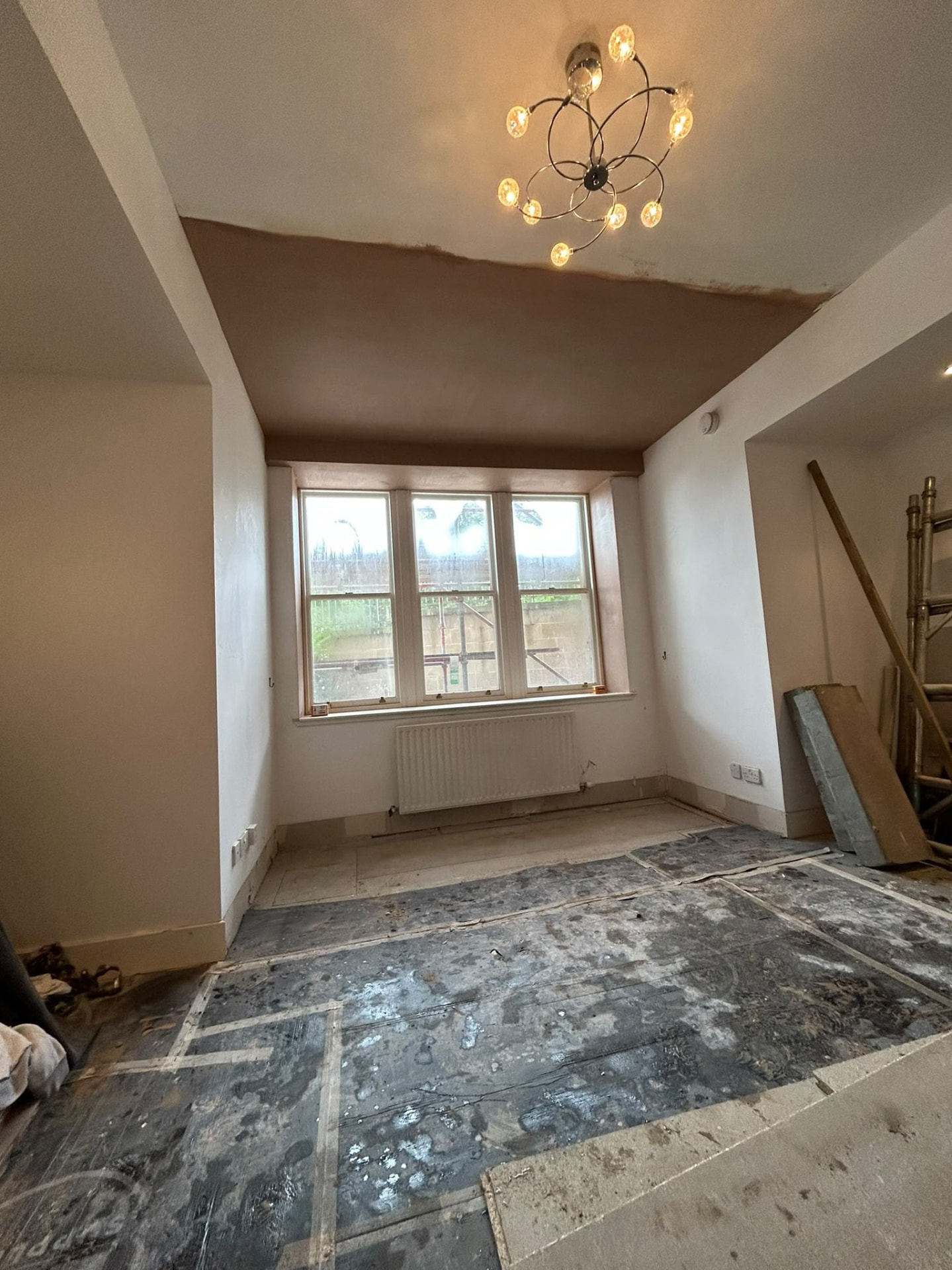 Bay window room part way through re-skimming with fresh plaster on the ceiling